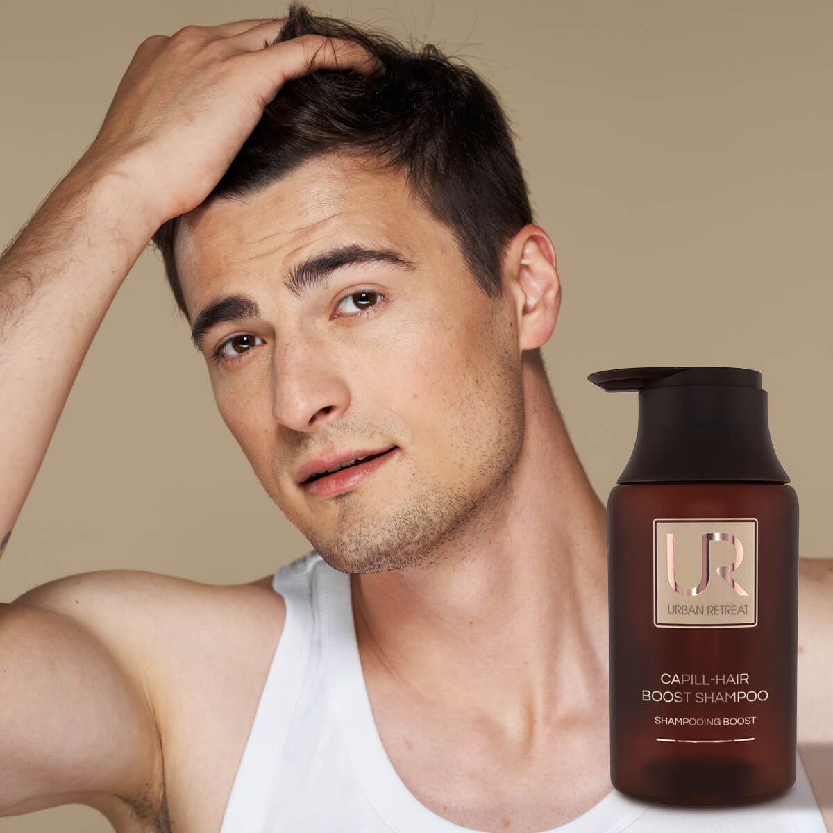 Man with a bottle of Urban Retreat Hair Capill-Hair Boost Shampoo on a beige background