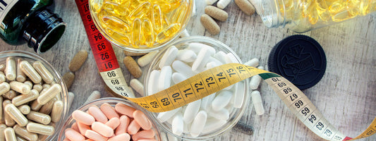 Assorted vitamins and supplements in various containers on a wooden surface.