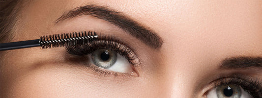Close-up of a woman applying mascara to her eyelashes.