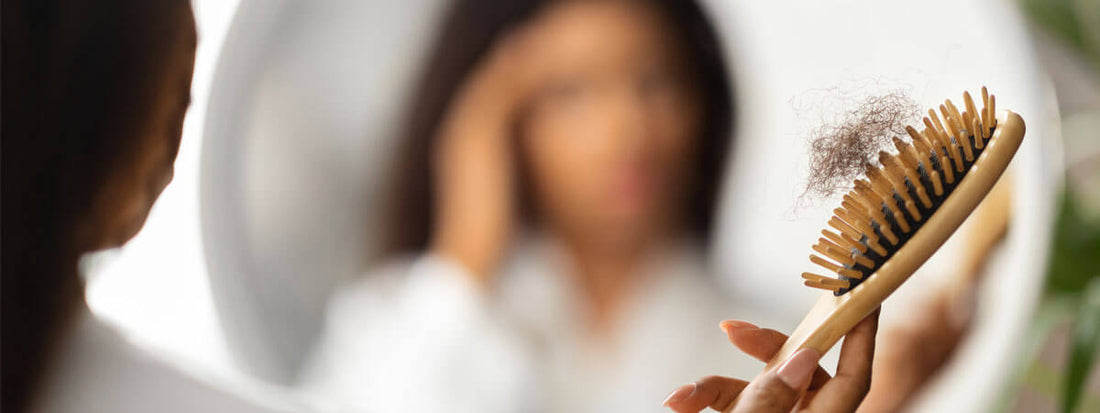 A woman brushing her hair while looking in a mirror.