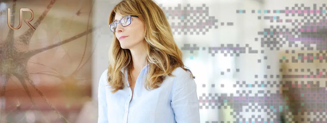 Woman with long hair and glasses standing in a modern, bright space.